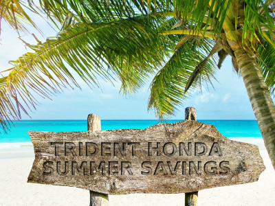 Beach with sign stating 'Trident Honda Summer Savings'