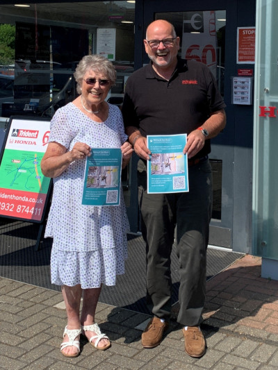 Mrs Thelma Forbes and Richard Roberts, Managing Director of Trident Honda, standing in front of our Ottershaw showroom and holding her sponsorship poster